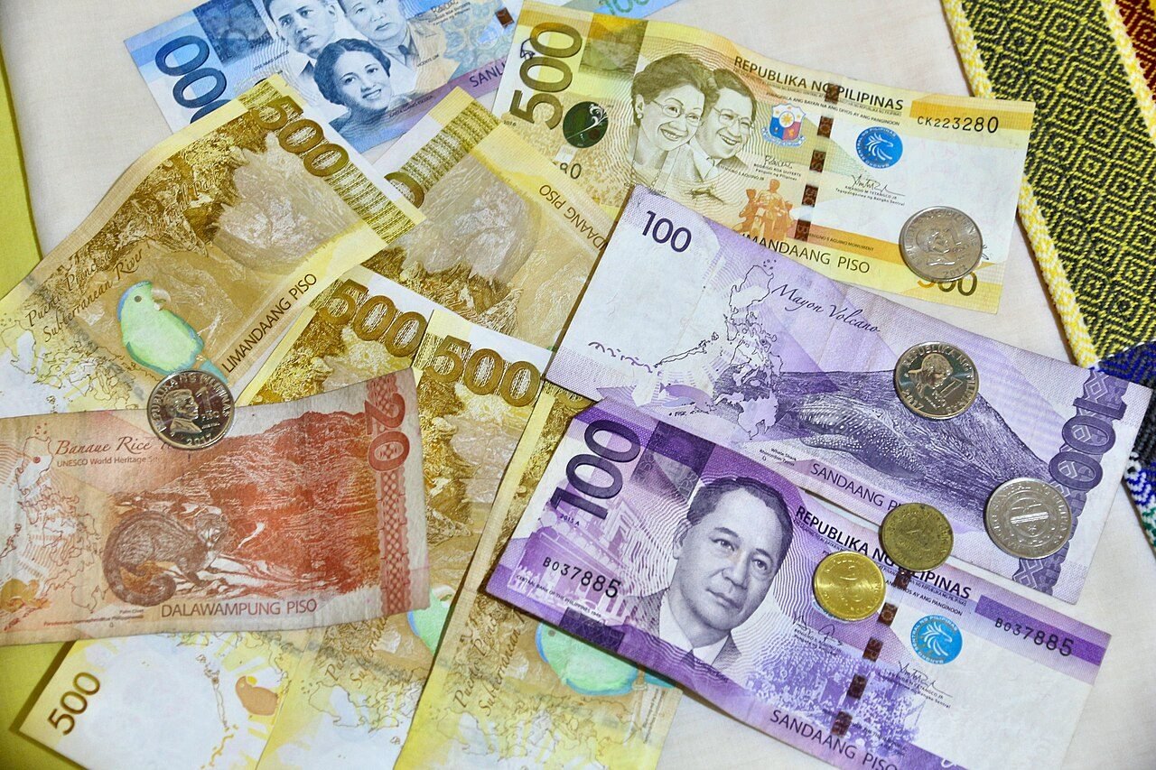 Philippine peso banknotes and coins fanned out, illustrating physical currency used in exchange