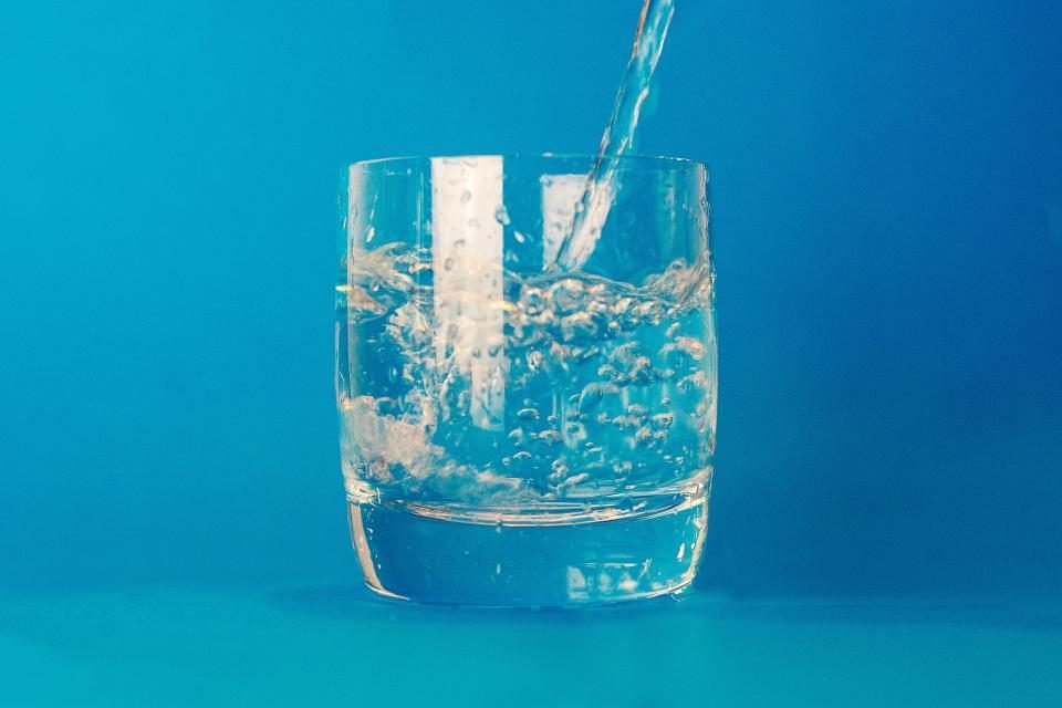 Clear glass filled with water photographed against a blue background