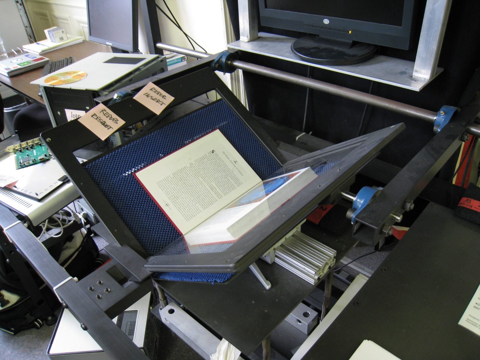 An open book positioned under an overhead book-scanning rig used to digitize printed pages