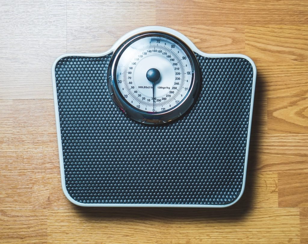 Bathroom weight scale on a wooden floor, representing body weight measurement used in BMI calculation